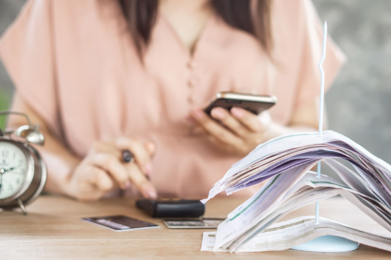 woman-hand-counting-expenses-phone-and-credit-cards-bills