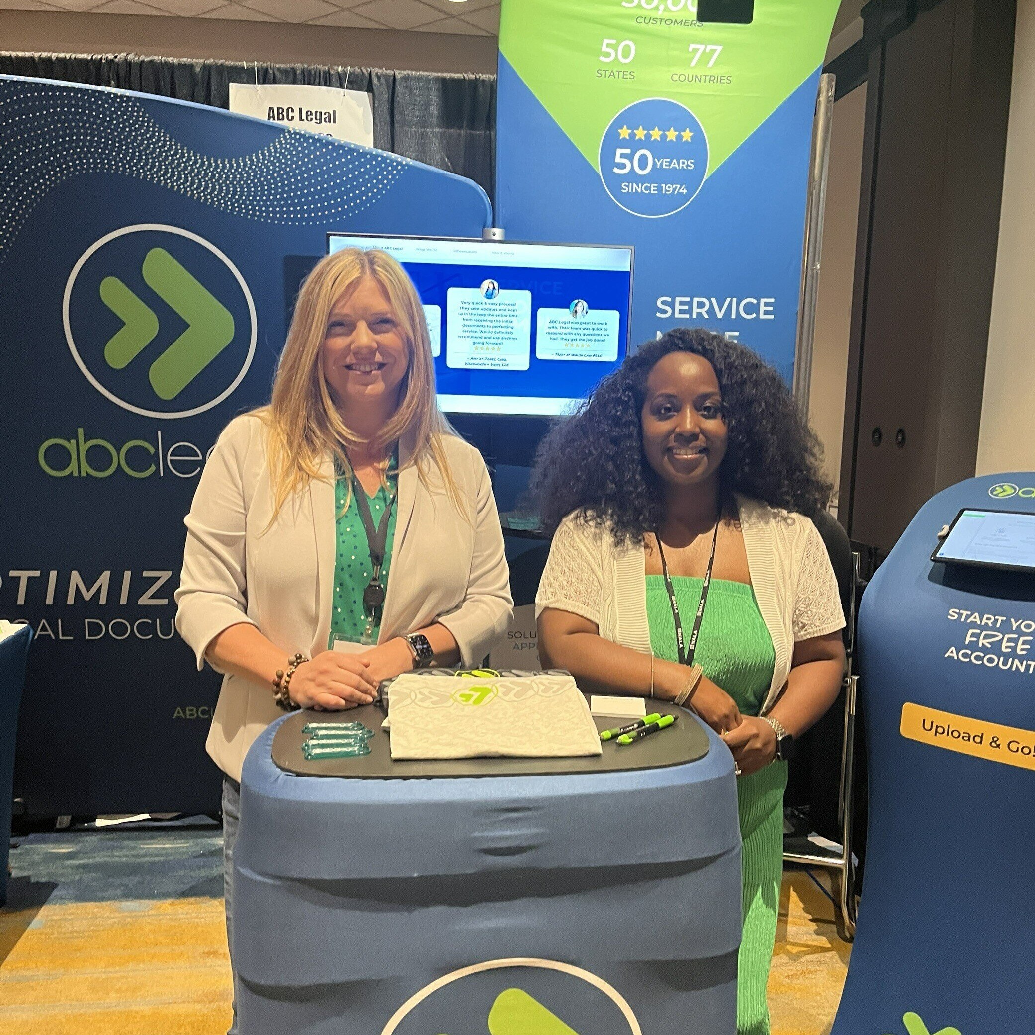 Two ABC Legal representatives at the NALA Annual Conference booth smiling at attendees.