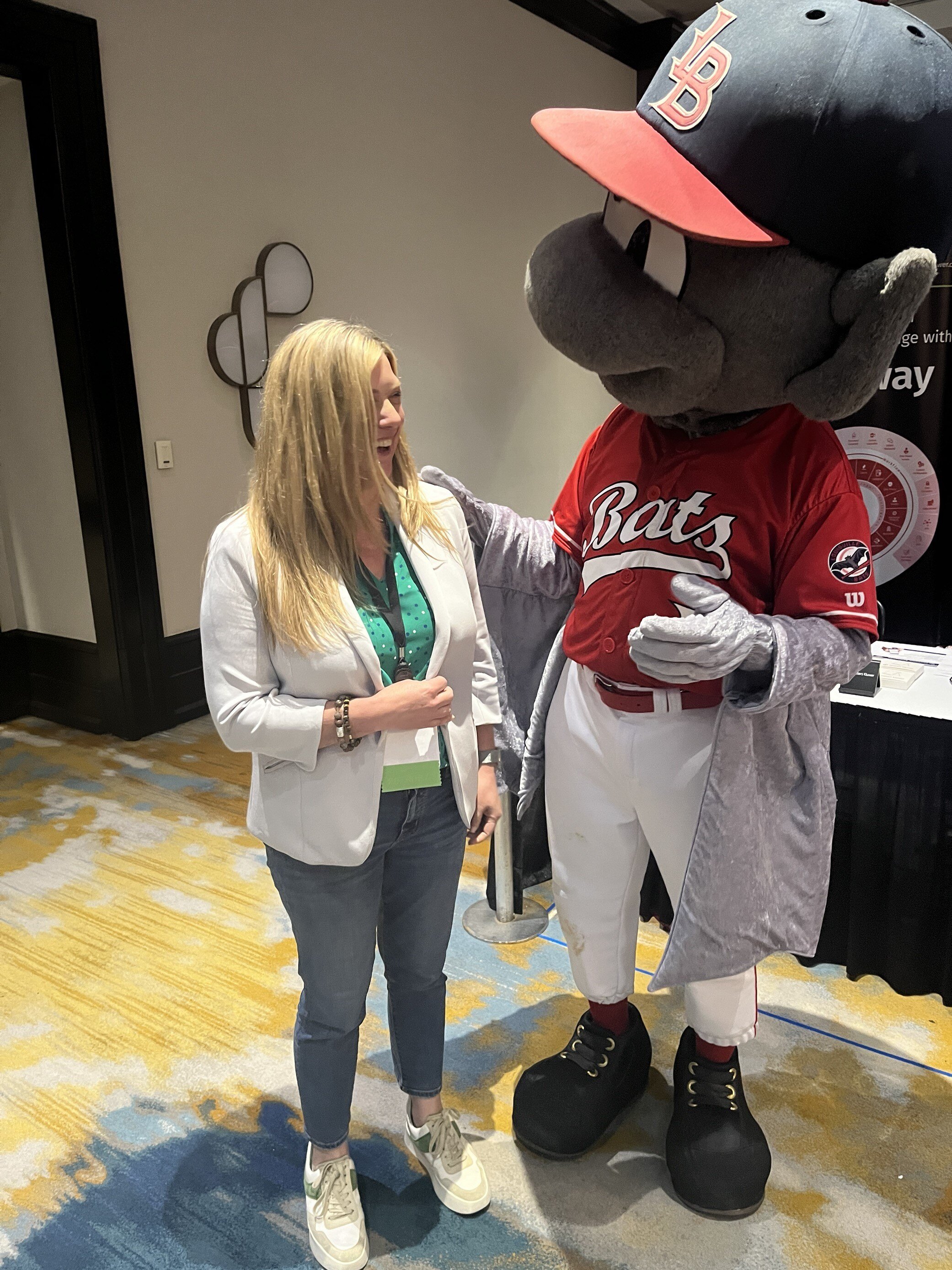 ABC Legal team member talking with Louisville Bats mascot during NALA event.