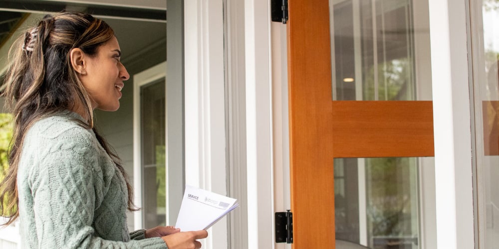 An ABC Legal process server greeting a recipient at an open door with papers in hand