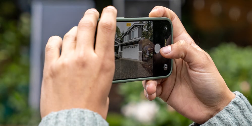 A process server photographing a home's driveway and garage as proof of service